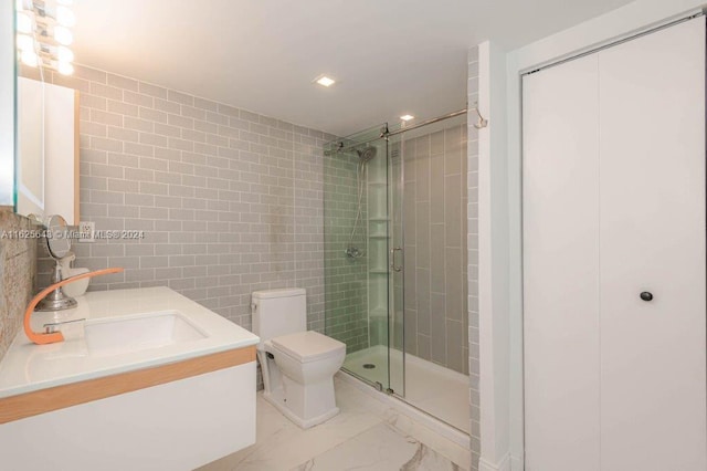 bathroom with vanity, toilet, a shower with door, and tile walls