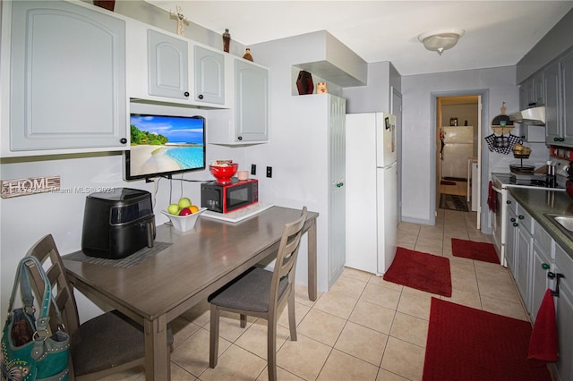 kitchen with white fridge, white cabinets, light tile patterned floors, and stainless steel stove