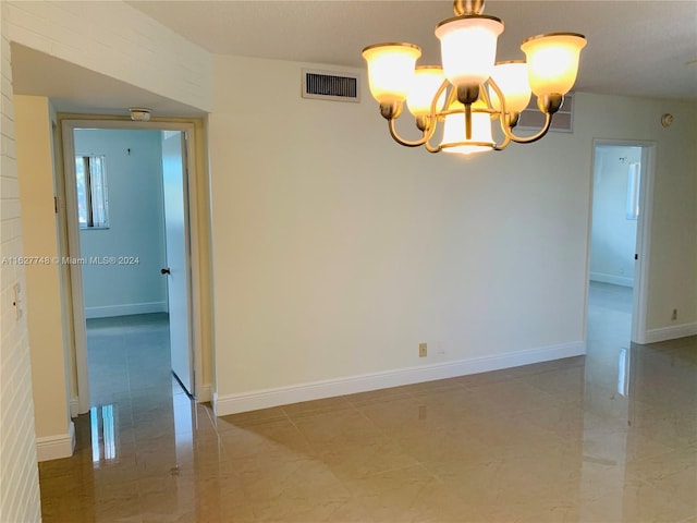 unfurnished room featuring tile patterned floors and an inviting chandelier