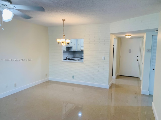 interior space with sink, light tile patterned flooring, a textured ceiling, and ceiling fan with notable chandelier