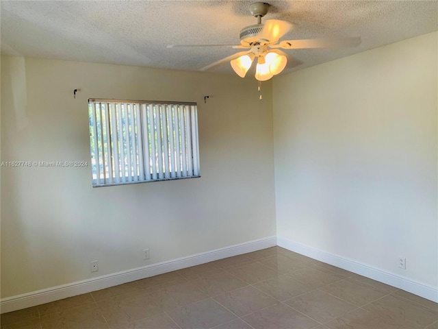 tiled spare room featuring a textured ceiling and ceiling fan