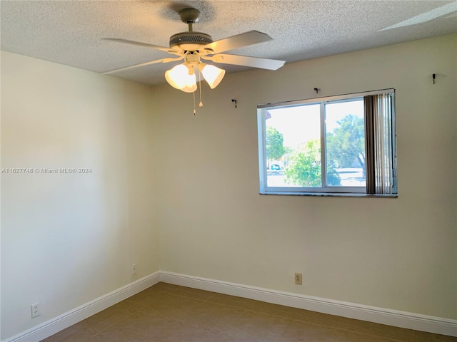 empty room featuring tile patterned flooring, ceiling fan, and a textured ceiling