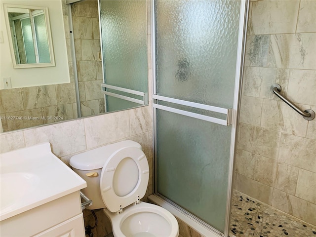 bathroom featuring vanity, walk in shower, toilet, and tile walls