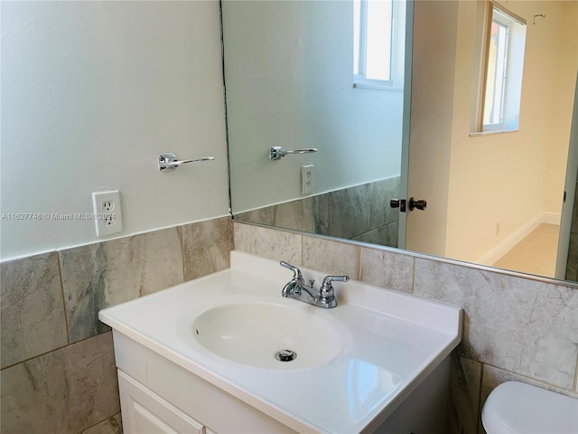 bathroom with vanity, toilet, and tile walls