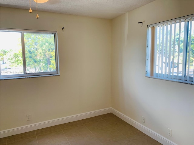 unfurnished room featuring light tile patterned floors, a wealth of natural light, and a textured ceiling