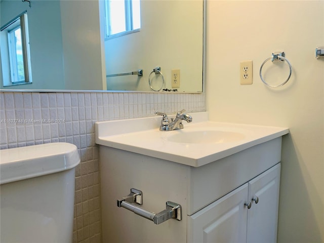 bathroom with vanity, a healthy amount of sunlight, toilet, and tile walls