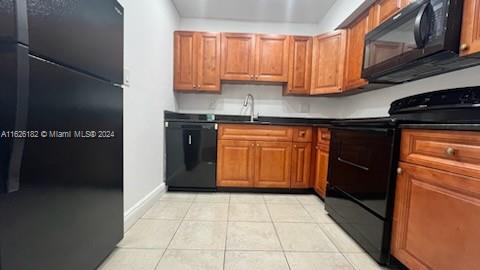 kitchen with black appliances, light tile patterned flooring, and sink