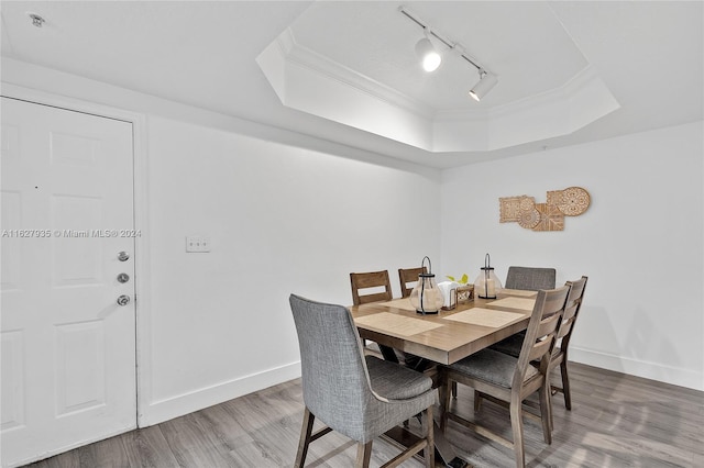 dining room featuring wood-type flooring, crown molding, a tray ceiling, and rail lighting