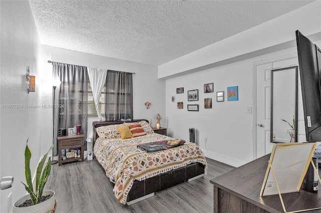 bedroom with hardwood / wood-style floors and a textured ceiling