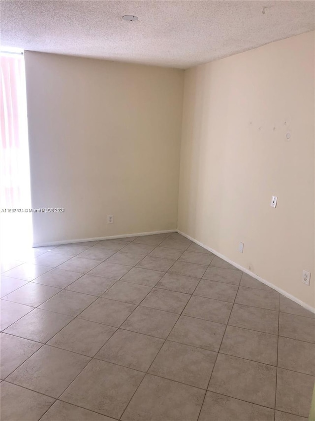 unfurnished room featuring a textured ceiling and light tile patterned floors