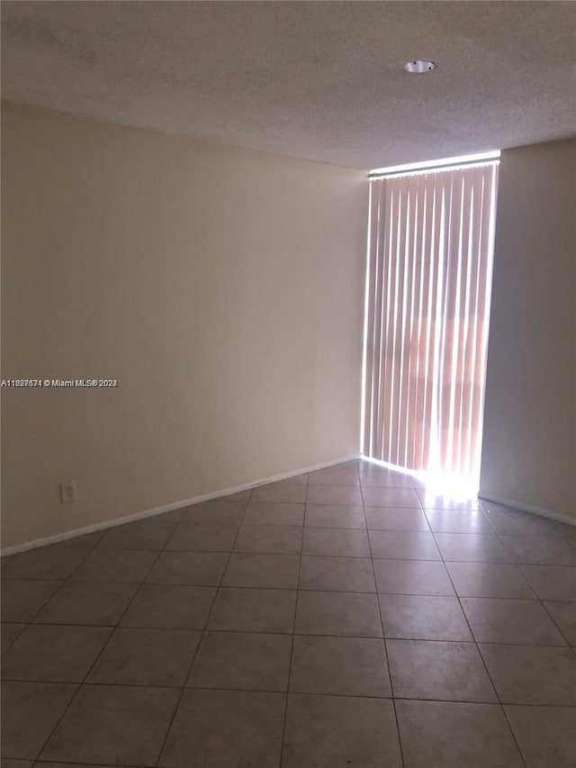 tiled spare room featuring a textured ceiling