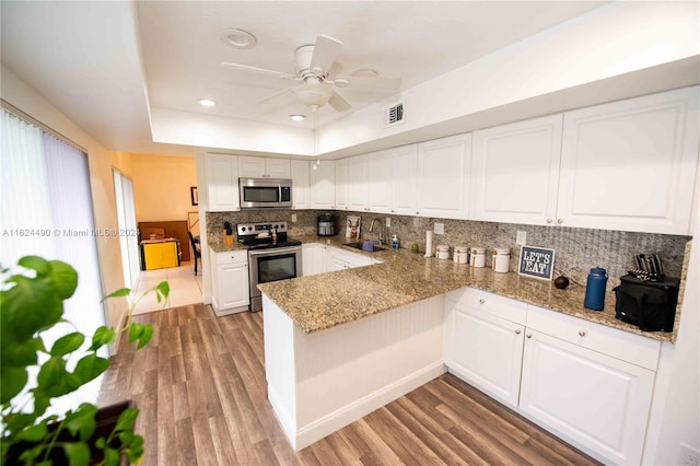 kitchen with appliances with stainless steel finishes, light hardwood / wood-style flooring, ceiling fan, and tasteful backsplash