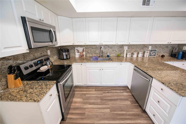 kitchen with decorative backsplash, light hardwood / wood-style flooring, white cabinets, sink, and stainless steel appliances