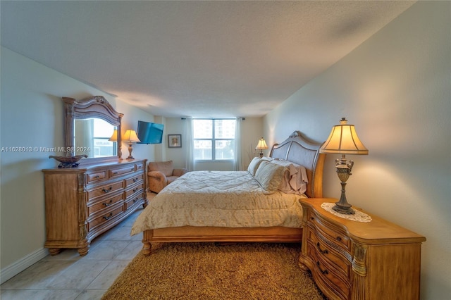 bedroom featuring light tile patterned floors, a textured ceiling, and baseboards