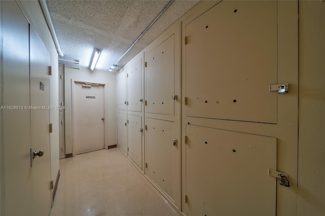 hallway featuring a textured ceiling and light floors