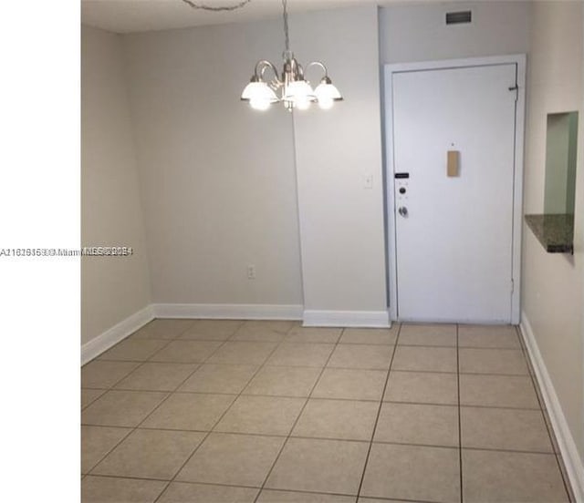 spare room with light tile patterned flooring and a chandelier