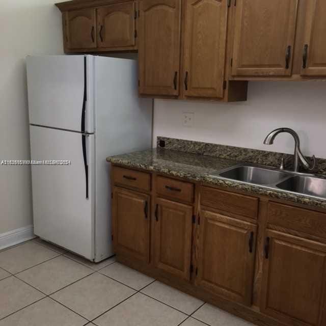 kitchen featuring light tile patterned floors, white refrigerator, and sink