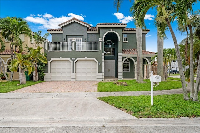 mediterranean / spanish home with a balcony, a front yard, and a garage