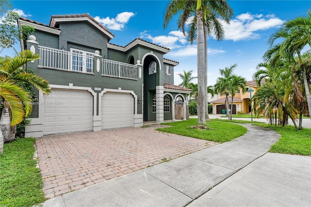 mediterranean / spanish house featuring stucco siding, decorative driveway, a garage, a balcony, and a tiled roof