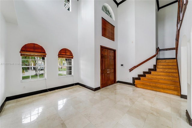 foyer entrance featuring a towering ceiling and light tile patterned flooring