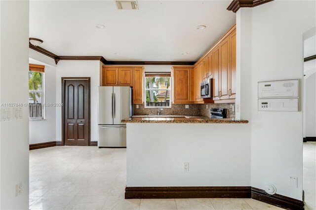 kitchen featuring tasteful backsplash, stone countertops, appliances with stainless steel finishes, light tile patterned floors, and kitchen peninsula