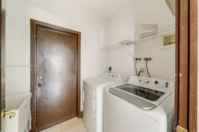 laundry area with washer and clothes dryer and light tile patterned floors