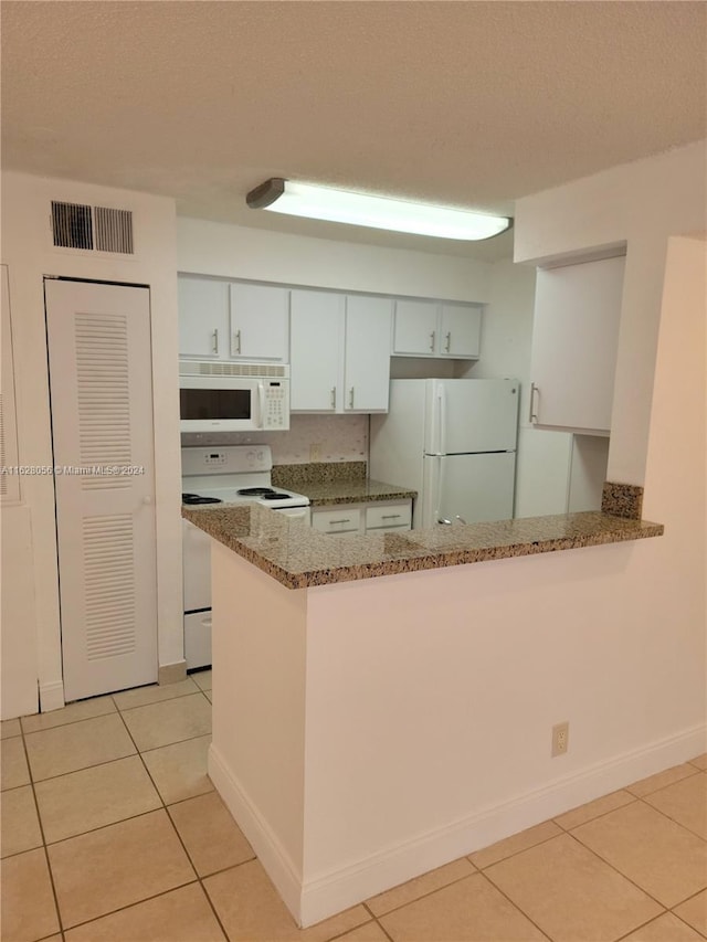 kitchen with white appliances, light tile patterned floors, light stone counters, white cabinetry, and kitchen peninsula