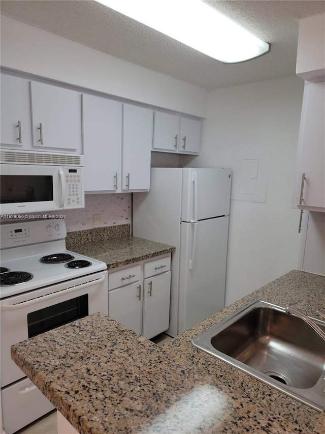 kitchen featuring white appliances, white cabinetry, sink, and light stone countertops