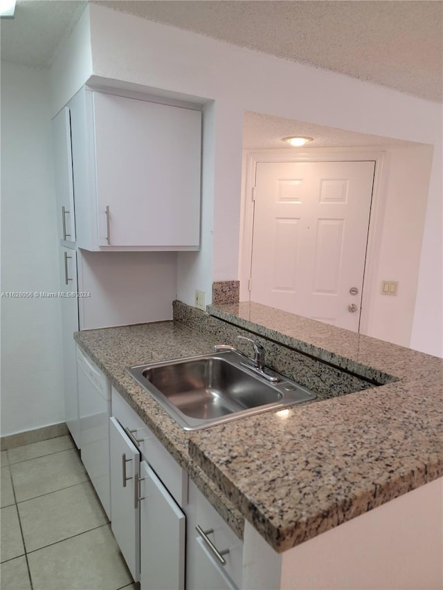 kitchen featuring sink, white cabinets, light tile patterned flooring, and white dishwasher