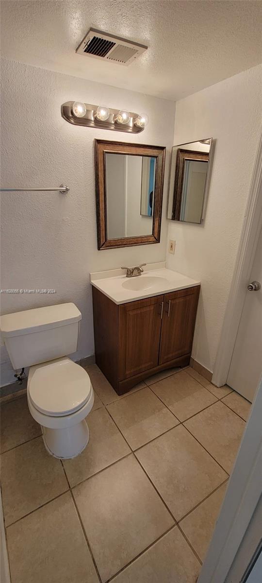 bathroom featuring a textured ceiling, vanity, toilet, and tile patterned floors