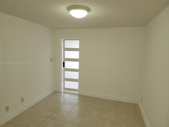 tiled empty room with a textured ceiling