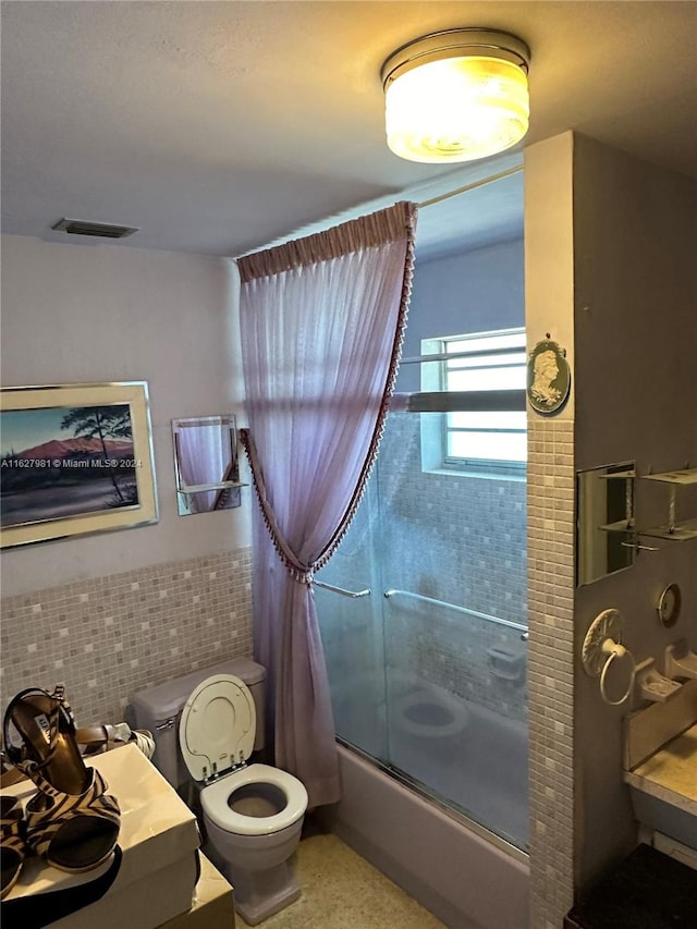 full bath with shower / bath combination with glass door, tile walls, visible vents, toilet, and speckled floor