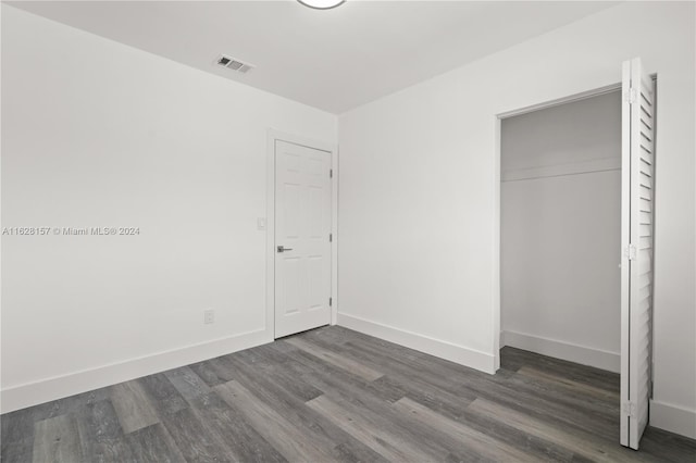 unfurnished bedroom with dark hardwood / wood-style floors and a closet