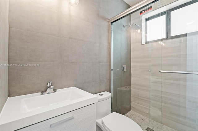 bathroom with tile walls, toilet, and walk in shower