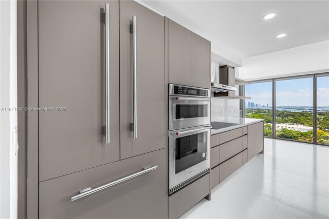 kitchen with gray cabinetry, light tile patterned flooring, a wall of windows, and appliances with stainless steel finishes