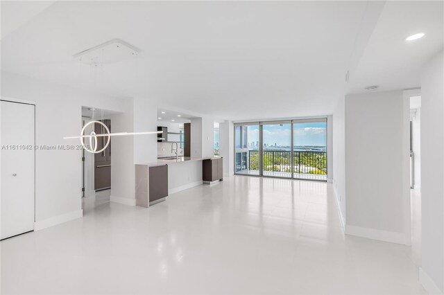 unfurnished living room with a wall of windows and sink