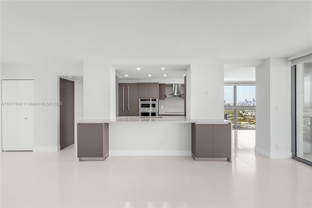 kitchen with kitchen peninsula, floor to ceiling windows, dark brown cabinets, and wall chimney exhaust hood