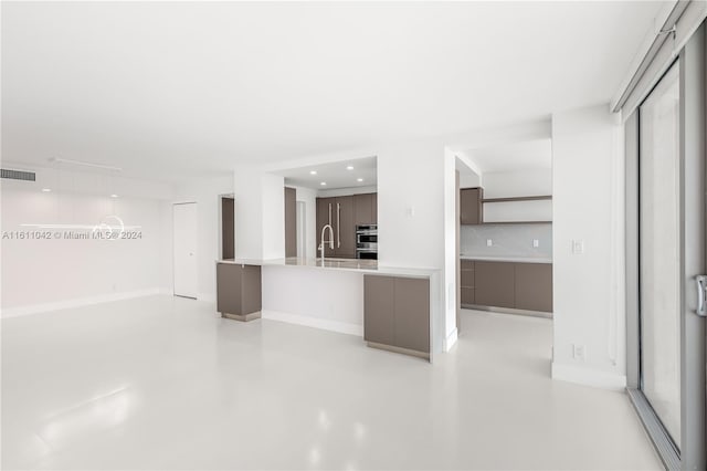 kitchen with dark brown cabinetry, sink, double oven, and tasteful backsplash