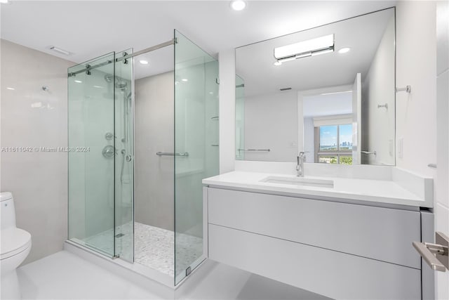 bathroom with a shower with door, vanity, and toilet