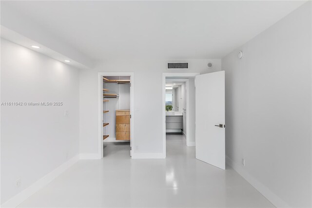 unfurnished bedroom featuring a walk in closet, a closet, and concrete floors