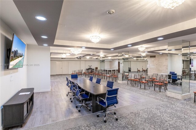 dining area featuring a raised ceiling, light hardwood / wood-style flooring, and an inviting chandelier