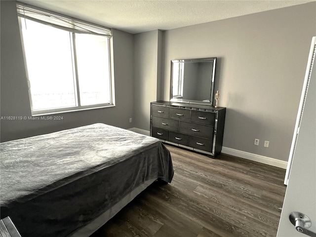 bedroom with dark hardwood / wood-style flooring and a textured ceiling