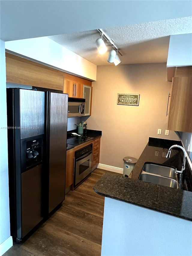 kitchen with a textured ceiling, dark hardwood / wood-style flooring, track lighting, appliances with stainless steel finishes, and sink