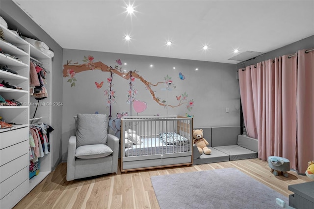 bedroom featuring a nursery area, wood finished floors, and recessed lighting