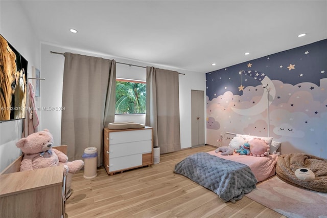 bedroom featuring an accent wall, recessed lighting, light wood finished floors, and wallpapered walls