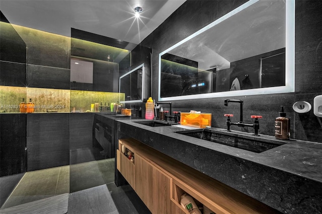 bathroom featuring tile patterned flooring, tile walls, decorative backsplash, and dual bowl vanity