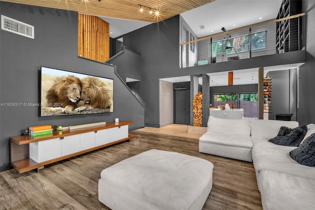 living room with visible vents, a towering ceiling, and wood finished floors