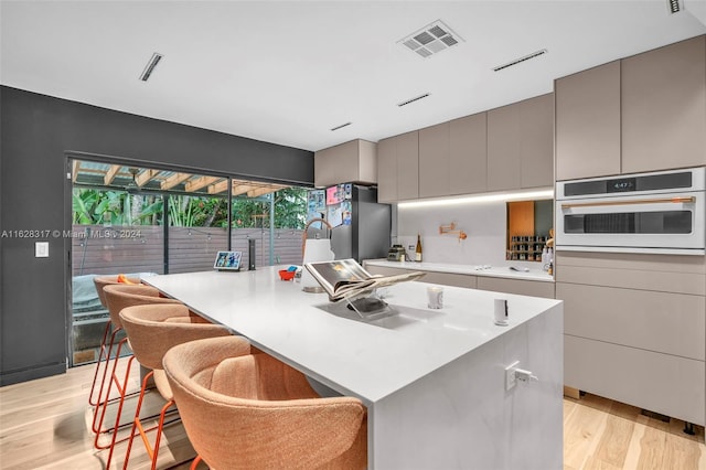 kitchen featuring white oven, gray cabinets, visible vents, light countertops, and light wood-type flooring