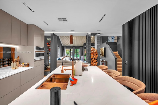 kitchen featuring gray cabinets, a kitchen breakfast bar, oven, and sink