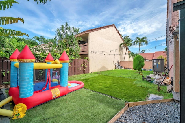 view of yard featuring a fenced backyard, central AC, and a playground